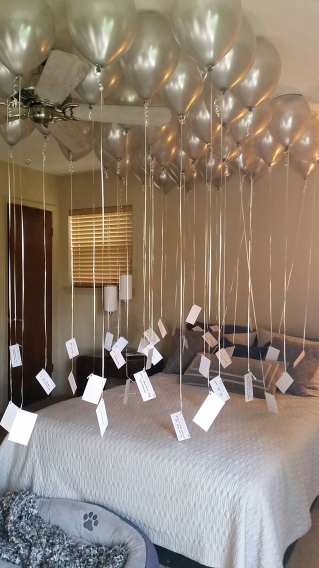 balloons are attached to the ceiling in front of a bed with sheets of paper on it