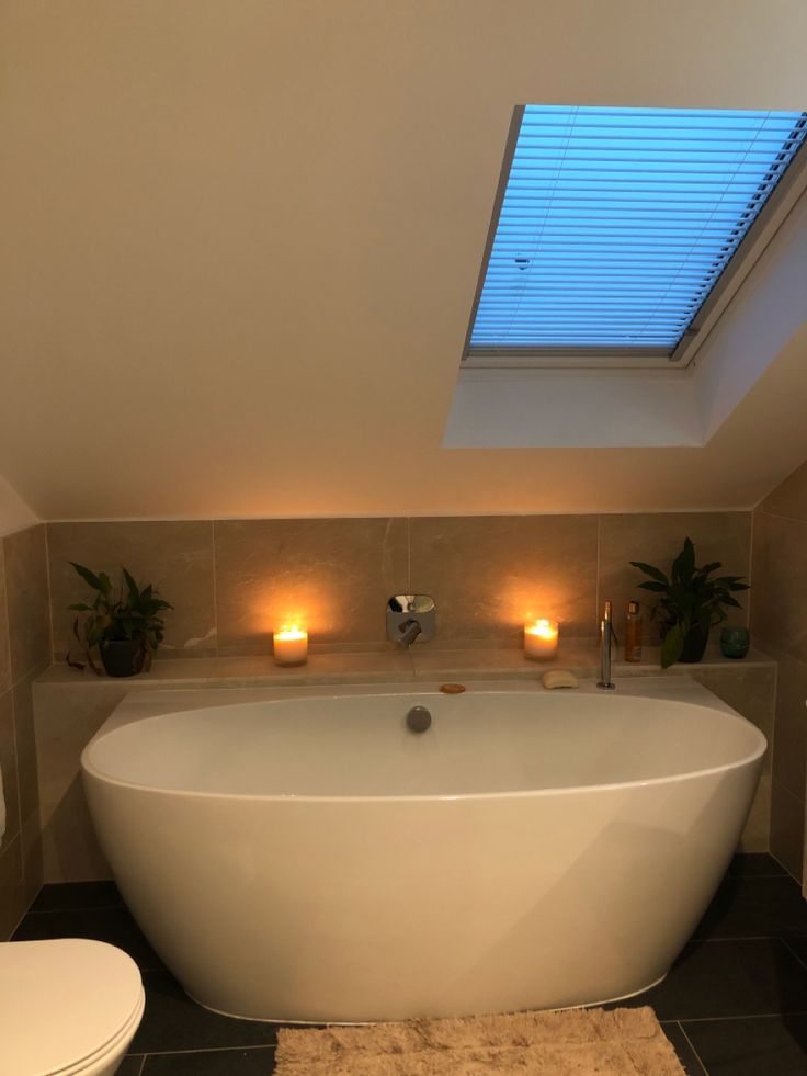 a large white bath tub sitting under a skylight