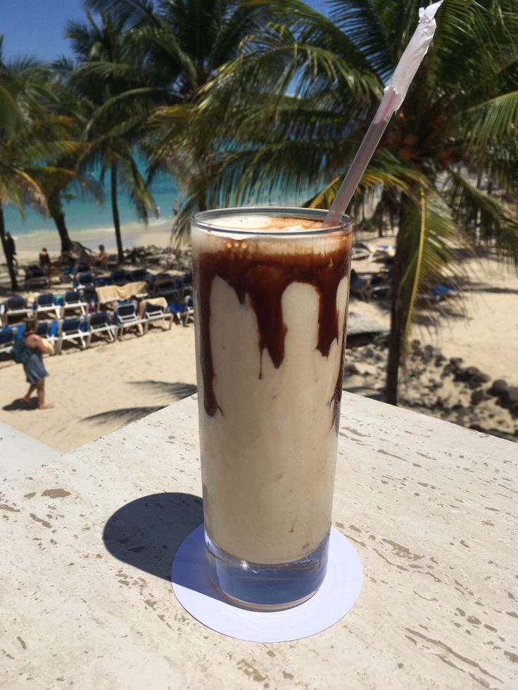 a drink sitting on top of a table next to the ocean