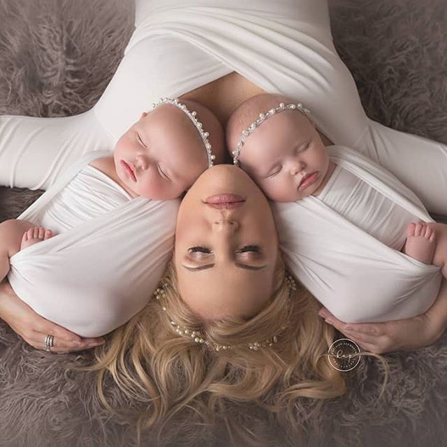 a woman is laying down with two babys on her back and the mother's head resting on her chest