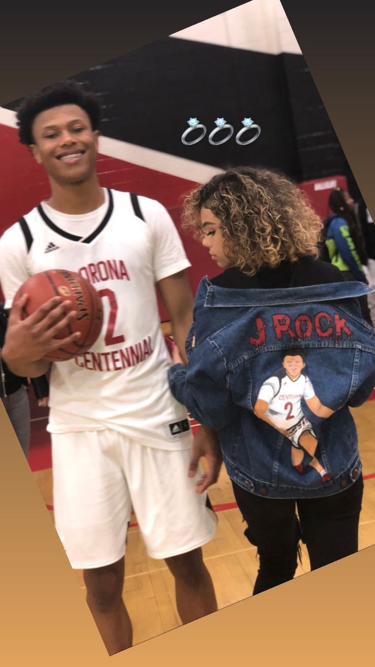 two people standing on a basketball court with one holding a ball and the other wearing a jean jacket