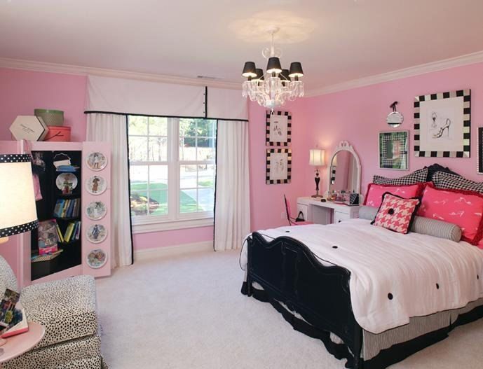 a bedroom with pink walls, black and white bedding, and chandelier