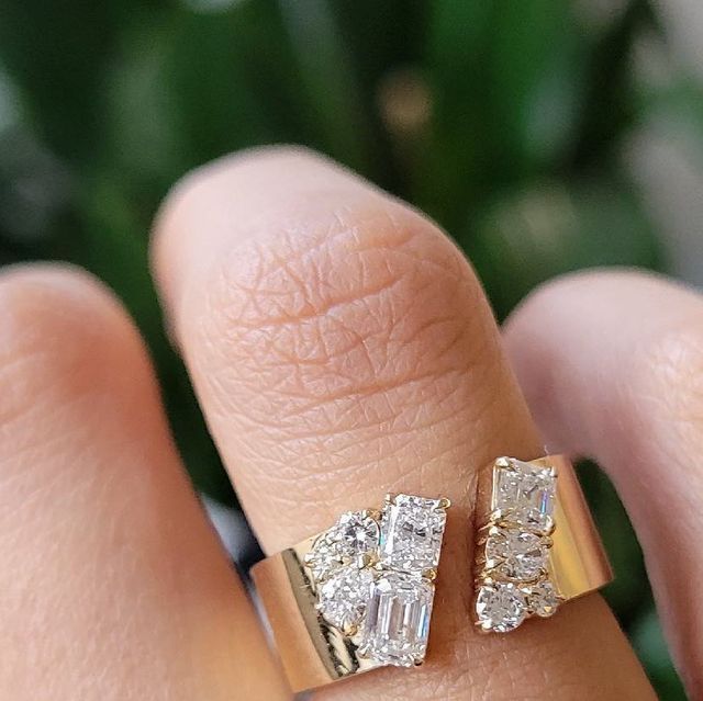 a woman's hand with two rings on it and a plant in the background