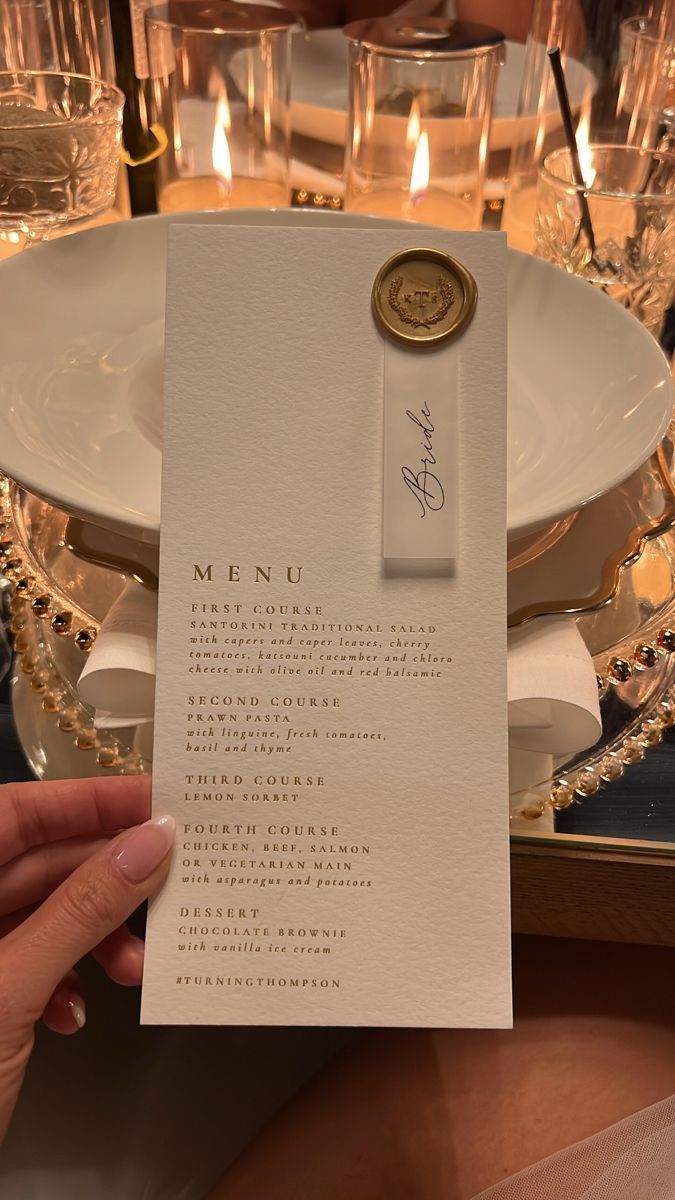 a person holding up a menu in front of a table with glasses and plates on it