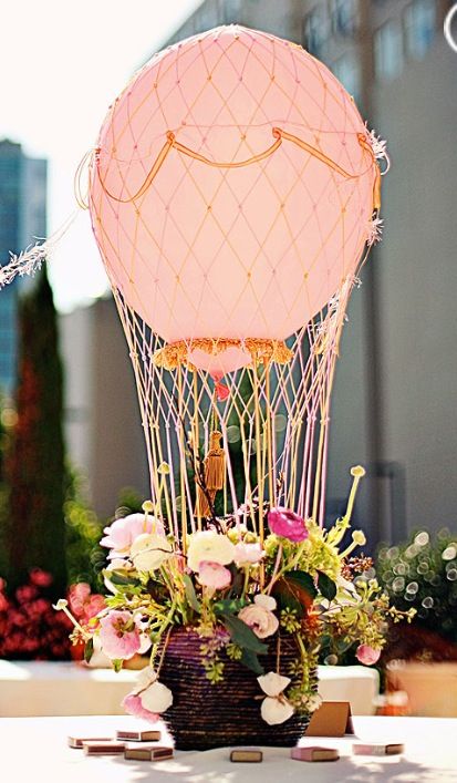 a table topped with a vase filled with flowers and a hot air balloon in the background