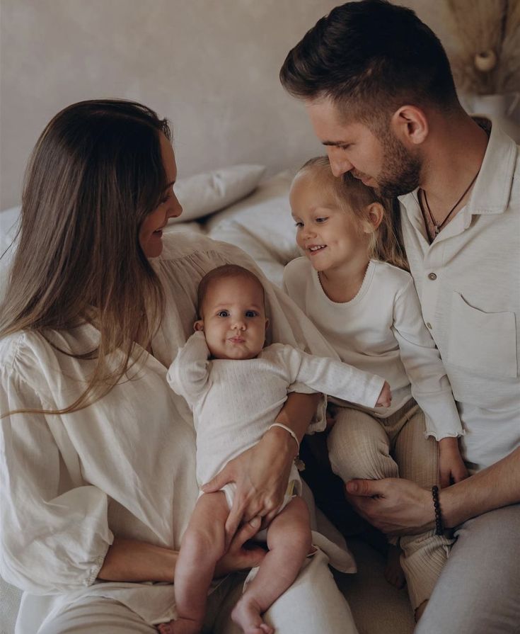 a man, woman and child are sitting on a bed with their arms around each other