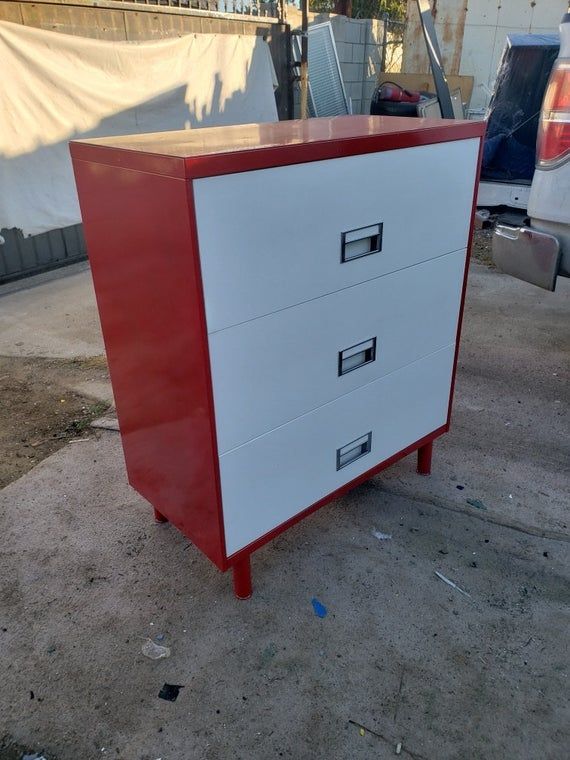 a red and white chest of drawers on the ground