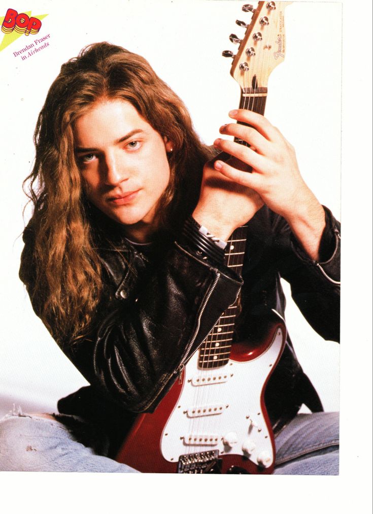 a man with long hair is holding an electric guitar and posing for the camera while wearing a black leather jacket