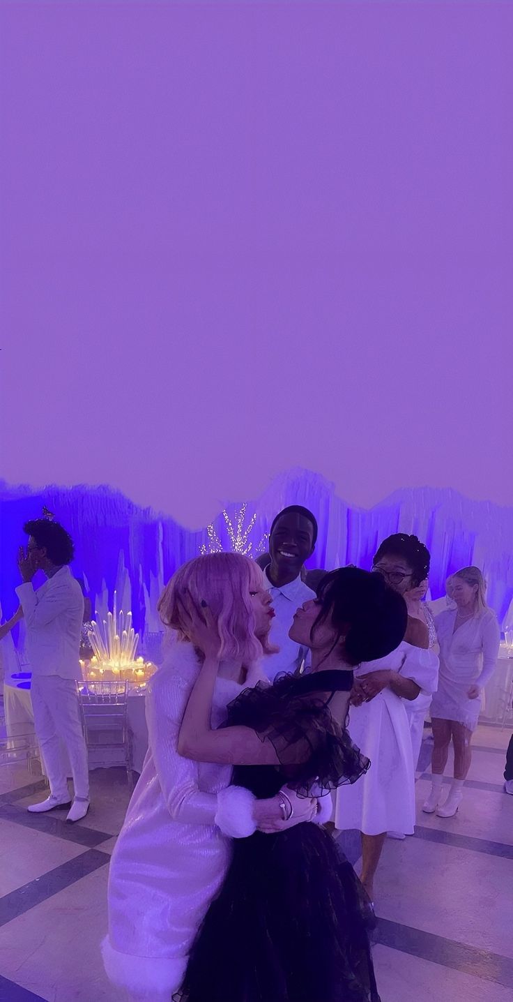 two women hugging each other in front of an audience at a wedding reception with purple lighting behind them