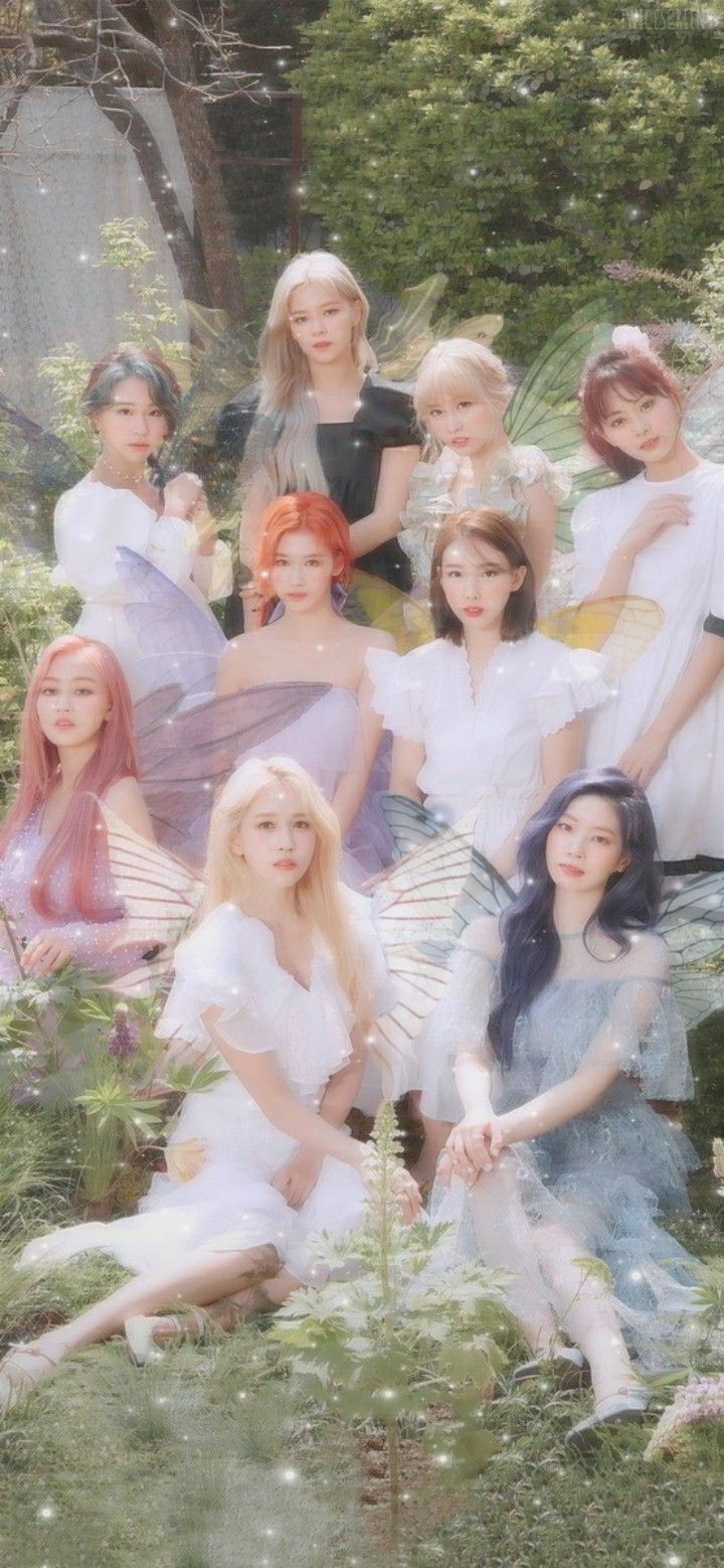 a group of young women in white dresses posing for a photo with trees and bushes behind them