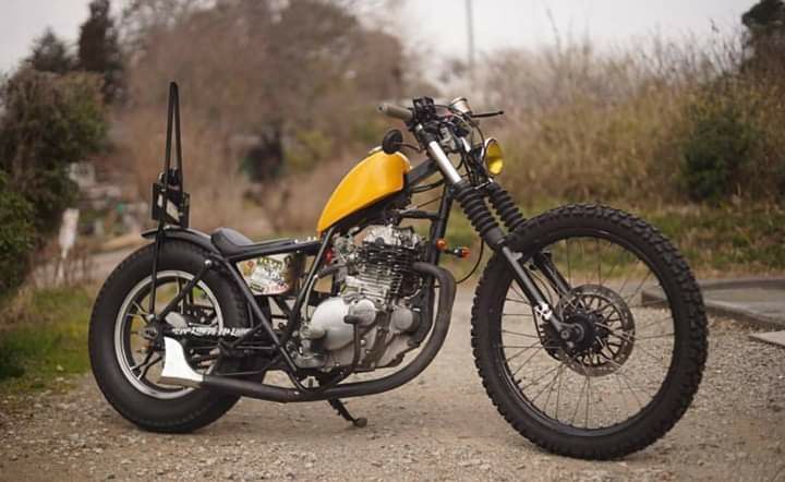 a yellow motorcycle parked on top of a dirt road