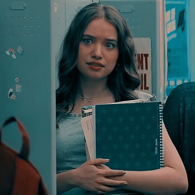 a woman holding a binder in front of her face and looking at the camera