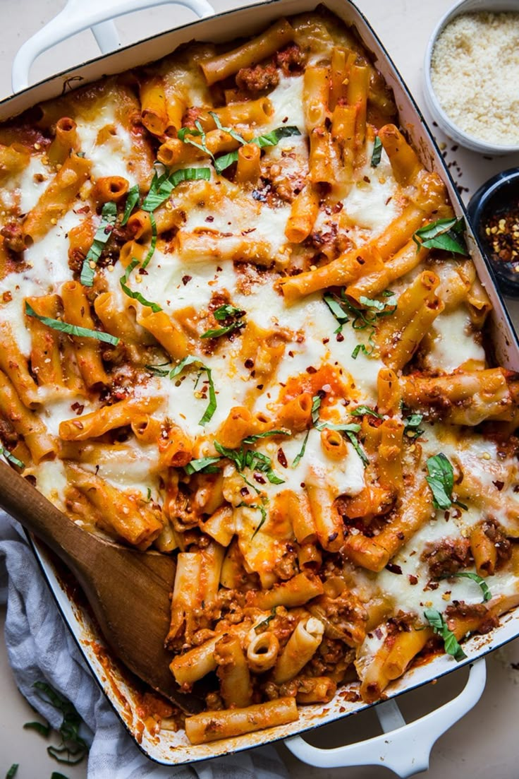 a casserole dish filled with pasta and meat, topped with parmesan cheese