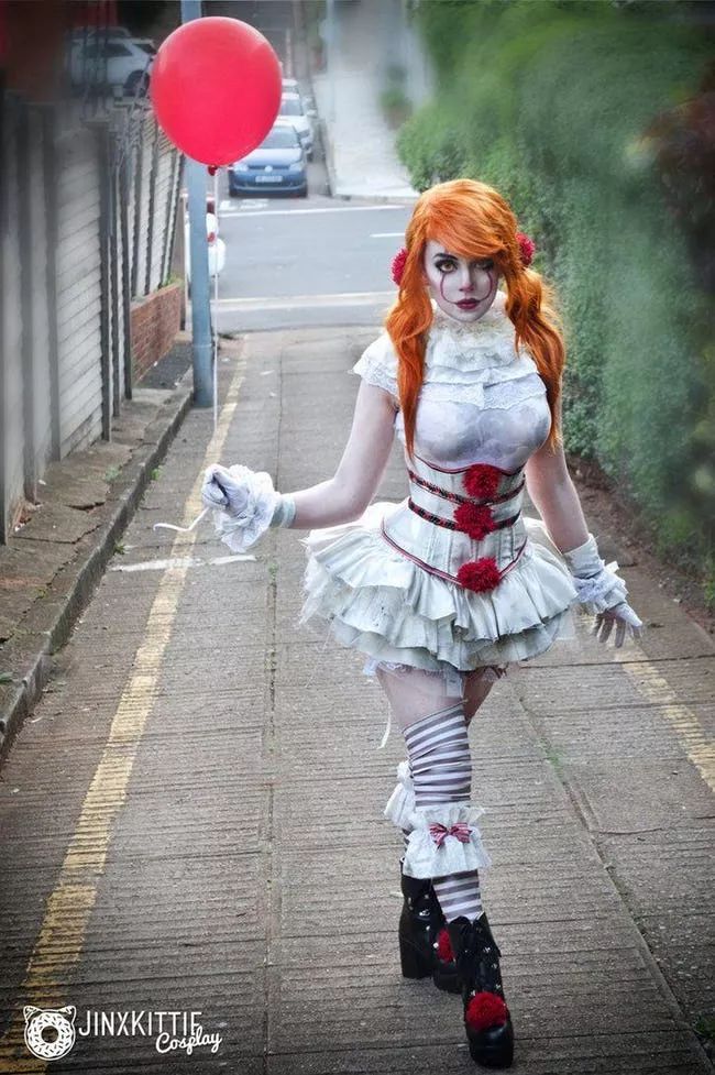 a woman dressed in white and red is walking down the street with a balloon behind her