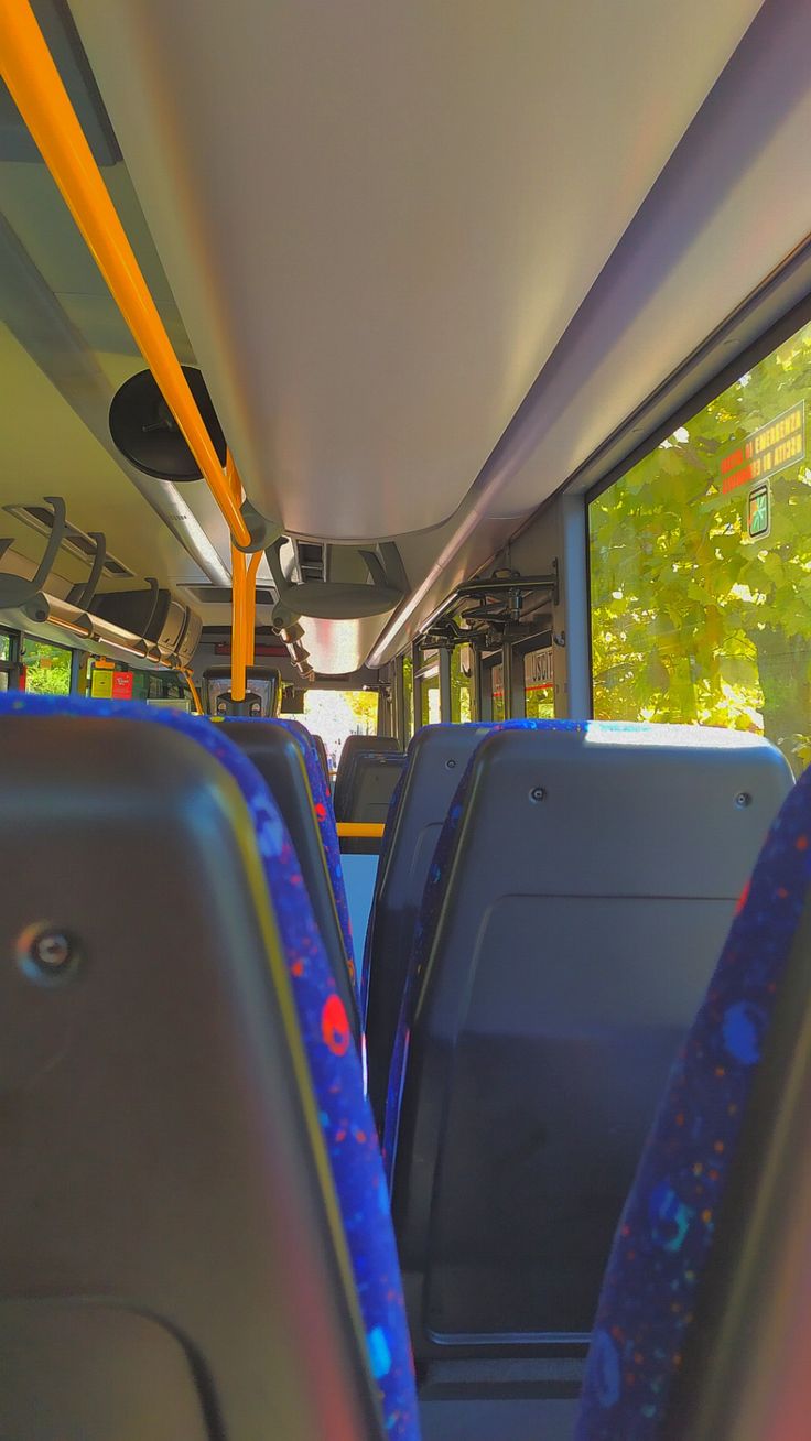 the interior of a public transit bus with blue seats and yellow poles, looking down at the floor