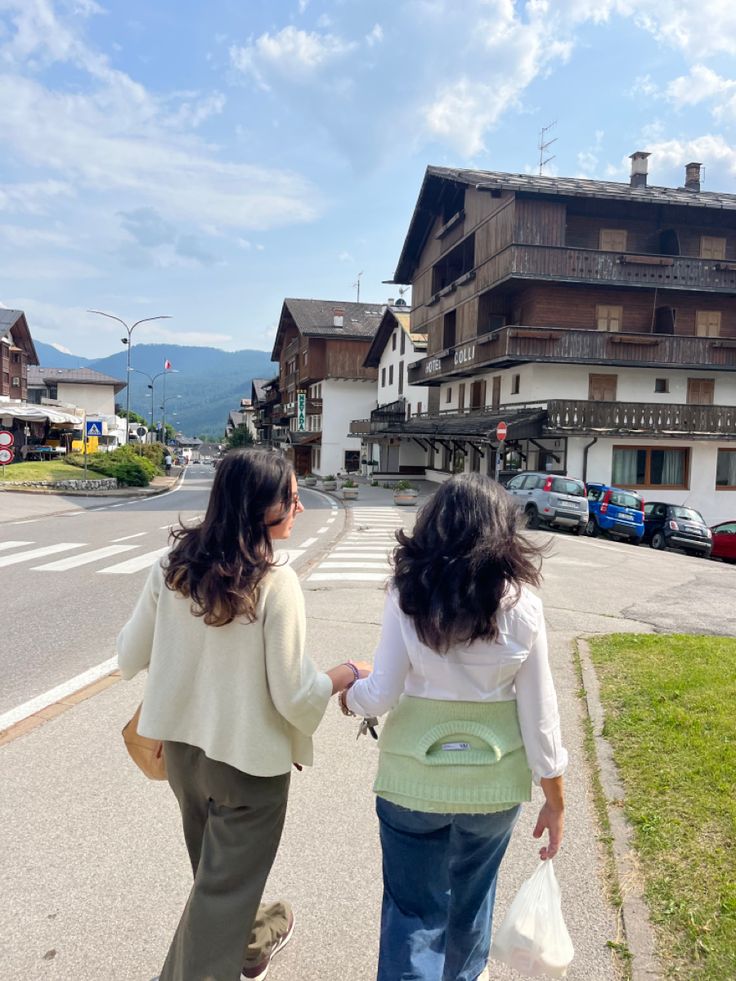 two women are walking down the street with bags in their hands and one is holding onto another woman's hand