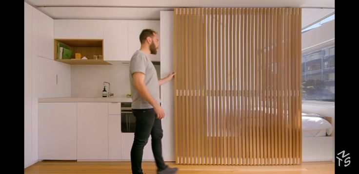 a man standing in front of a kitchen with wooden slats on the door and shelves