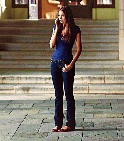 a woman talking on her cell phone while standing in front of some steps