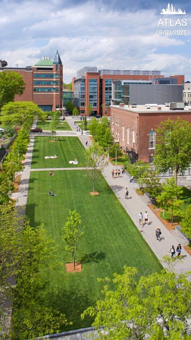 an aerial view of the campus with people walking and sitting on benches in the grass