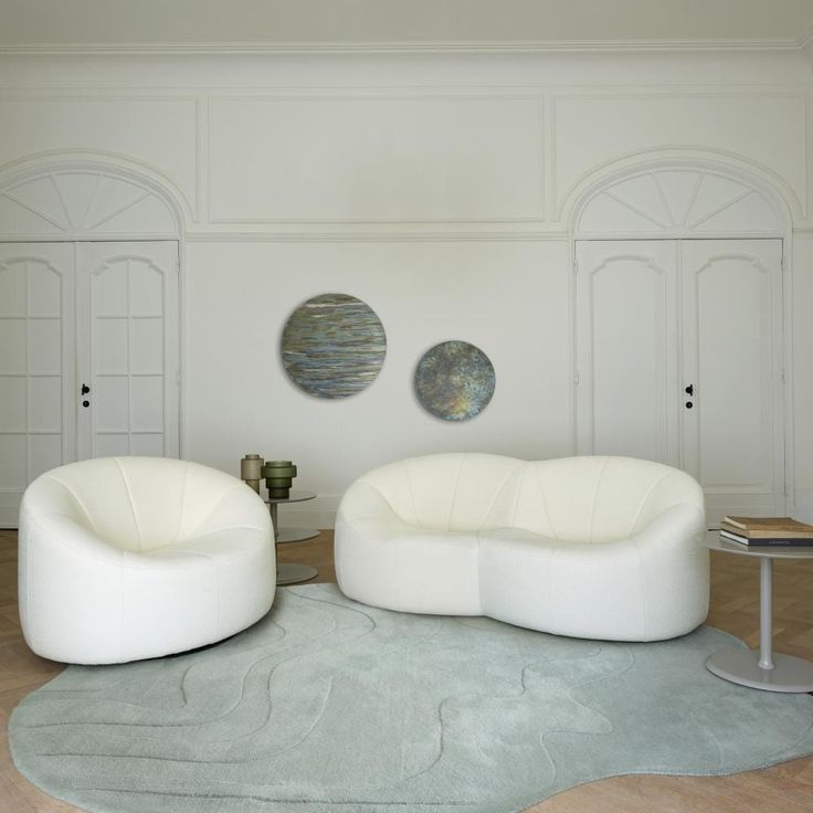 two white couches sitting on top of a rug in a living room next to each other