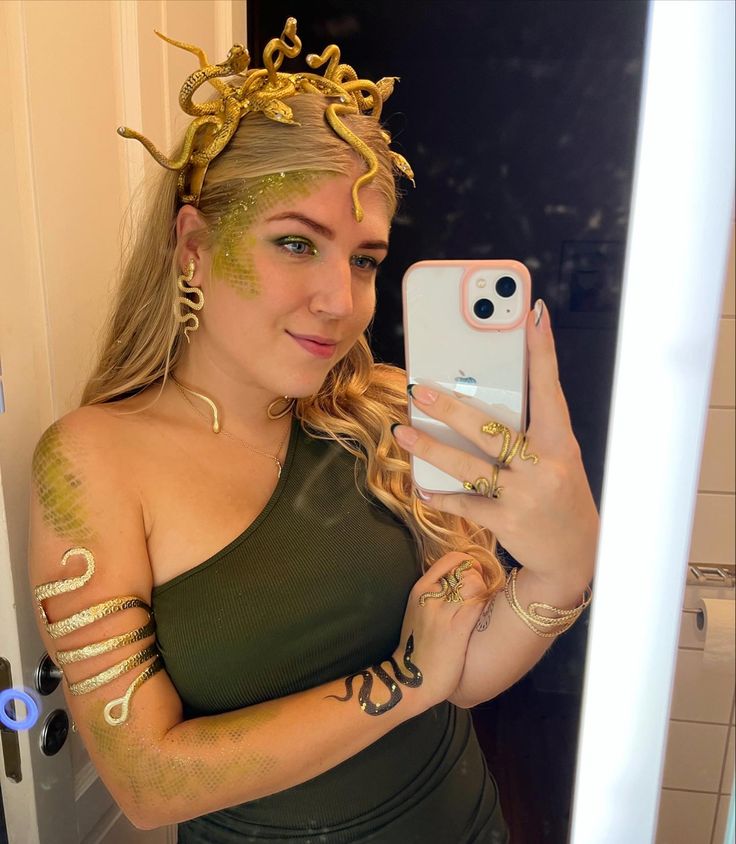 a woman taking a selfie with her cell phone wearing gold bracelets and tattoos