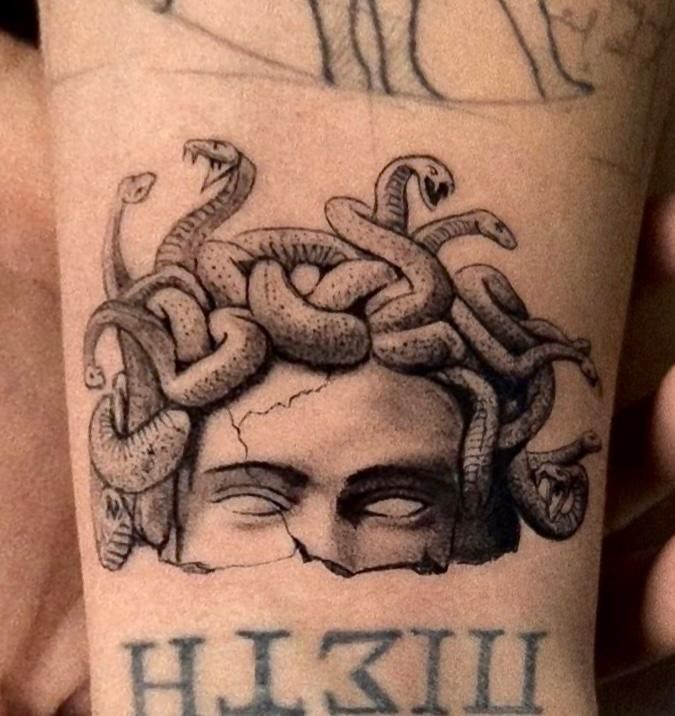 a man's arm with a drawing of a head and snakes on it