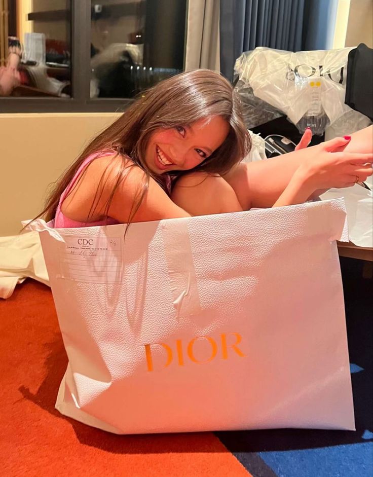 a woman sitting in a shopping bag on the floor with her legs up and one hand out