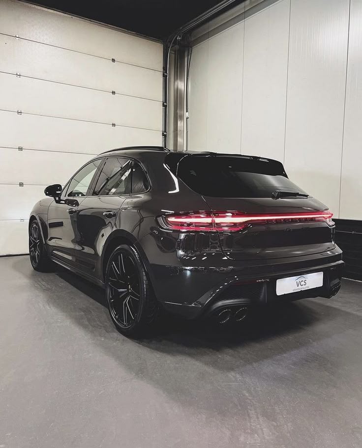 the rear end of a black car in a garage