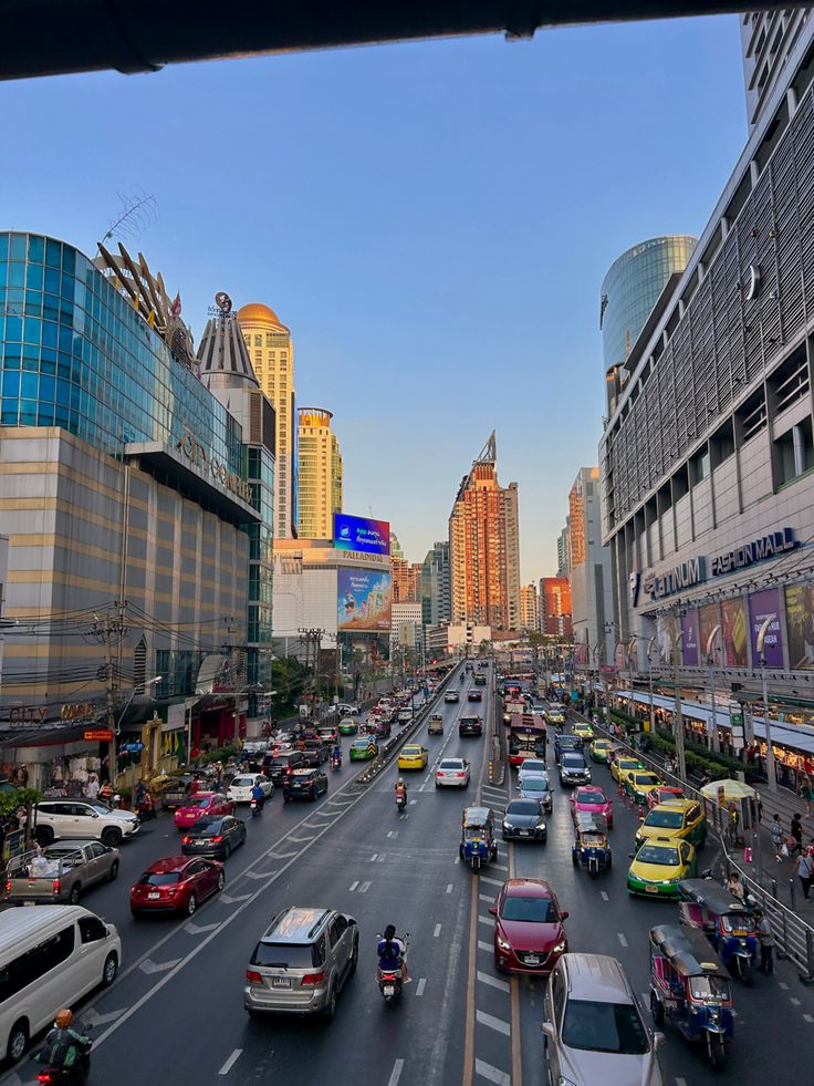 a city street filled with lots of traffic next to tall buildings on either side of the road