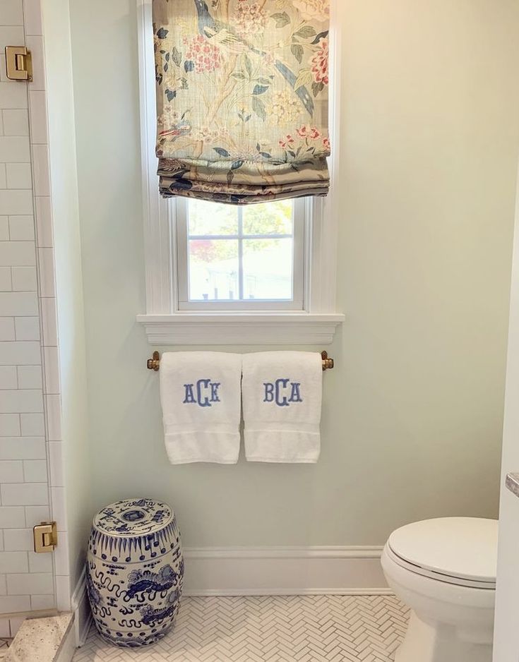 a white toilet sitting next to a window in a bathroom