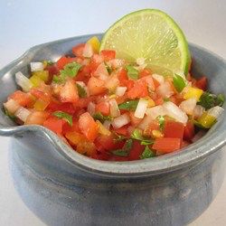 a small bowl filled with chopped vegetables and a lime wedged in the middle,