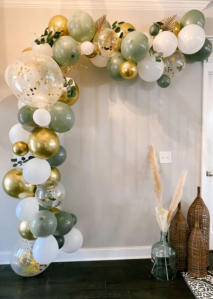 the balloon arch is decorated with gold, silver and white balloons