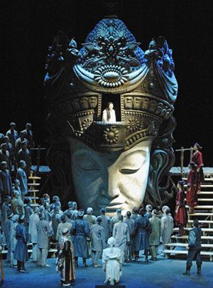 a large group of people standing on top of a stage next to a giant head