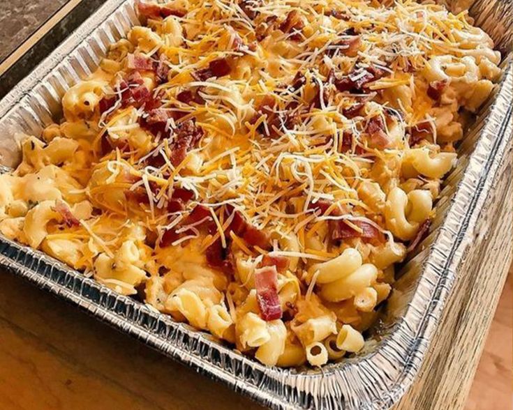 a casserole dish with bacon, cheese and pasta in it on a wooden table