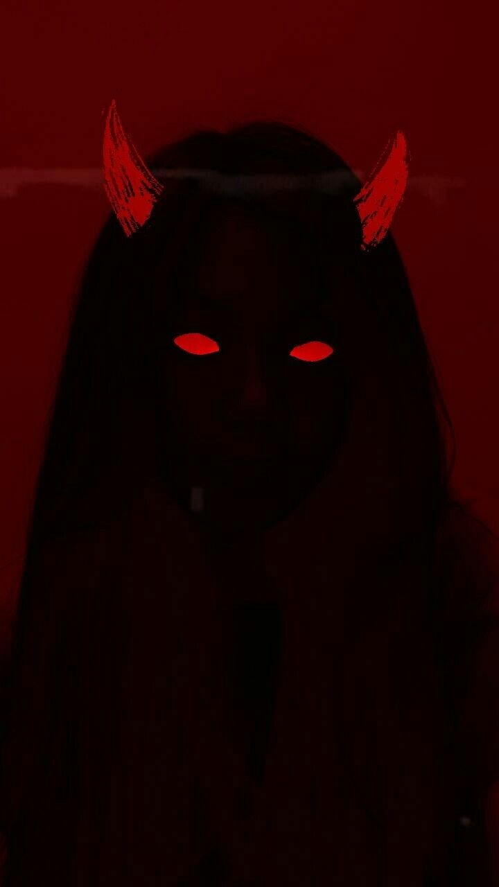 a woman with red eyes and devil horns on her head, in the dark at night