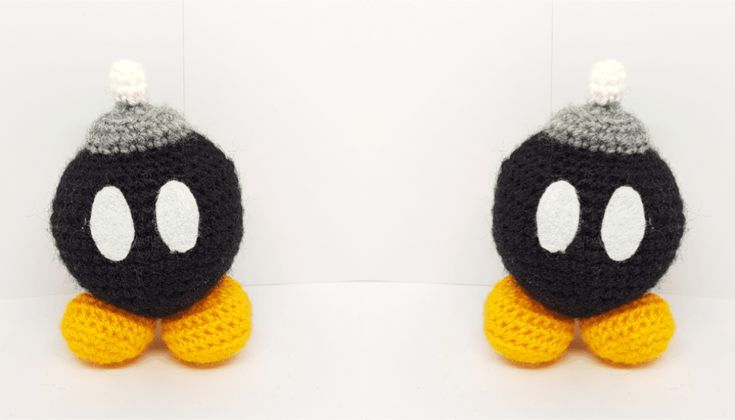 two black and white crocheted stuffed animals with yellow feet, one is wearing a hat