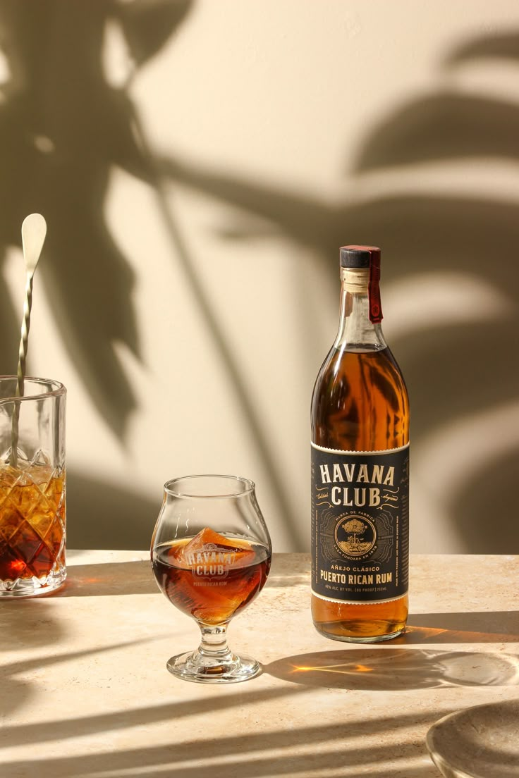 a bottle of havana club sitting next to a glass filled with liquid on a table