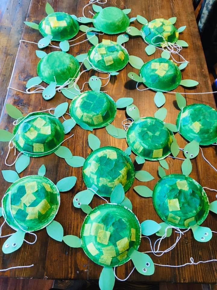 some paper plates are sitting on a table with green leaves and turtle heads painted on them