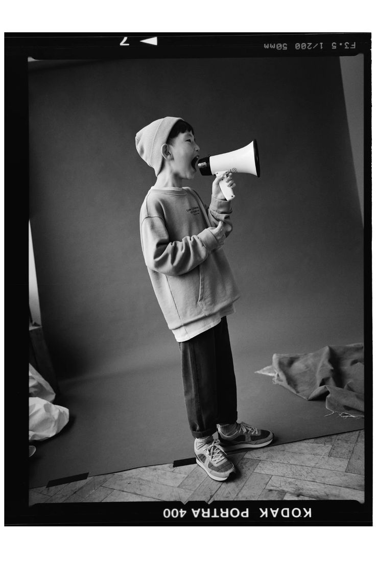 a young man holding a megaphone while standing in front of a black and white photo