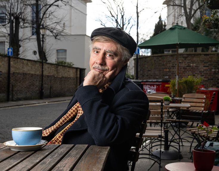 an older man sitting at a table with a cup of coffee in front of him