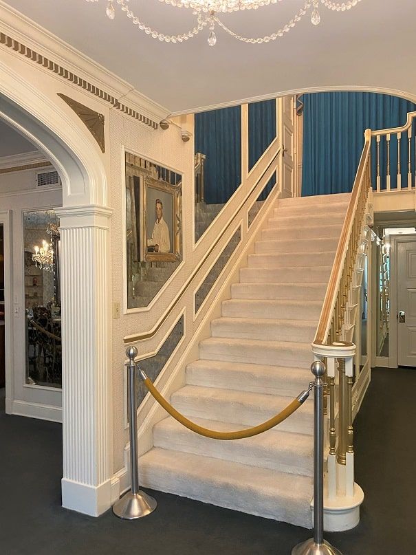 a staircase leading up to an entrance with a gold rope on the handrail and chandelier