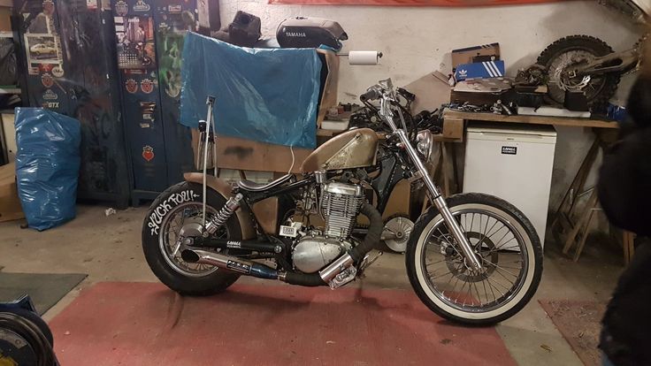 a motorcycle is parked in a garage with other items on the floor and behind it