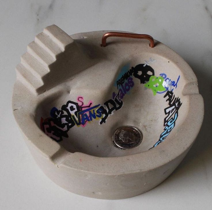 a white sink with graffiti on it sitting on a counter next to a small coin