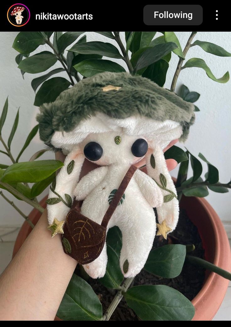 a stuffed animal in a potted plant with leaves on it's head and holding a stick