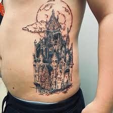 a man with a tattoo on his stomach that has a castle in the sky above it