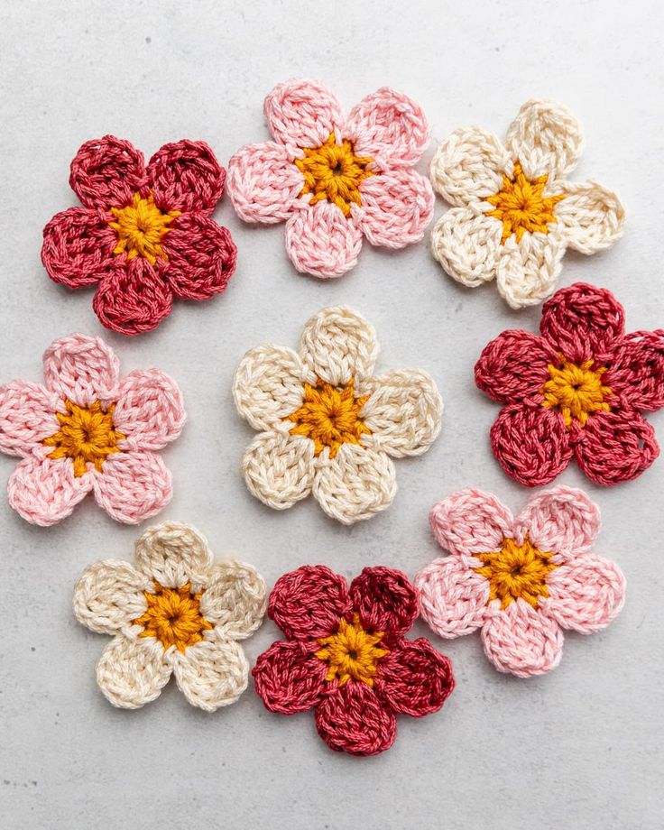 crocheted flowers are arranged in the shape of a circle on a white surface