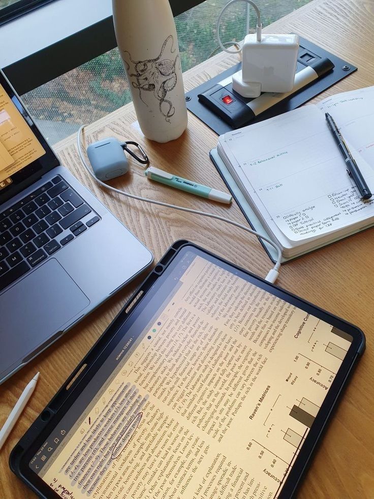 an open laptop computer sitting on top of a wooden desk next to a notebook and pen