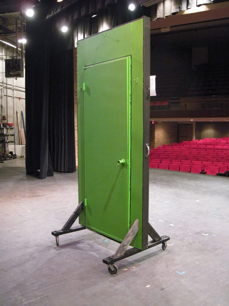 a large green box sitting in the middle of a stage with red seats behind it