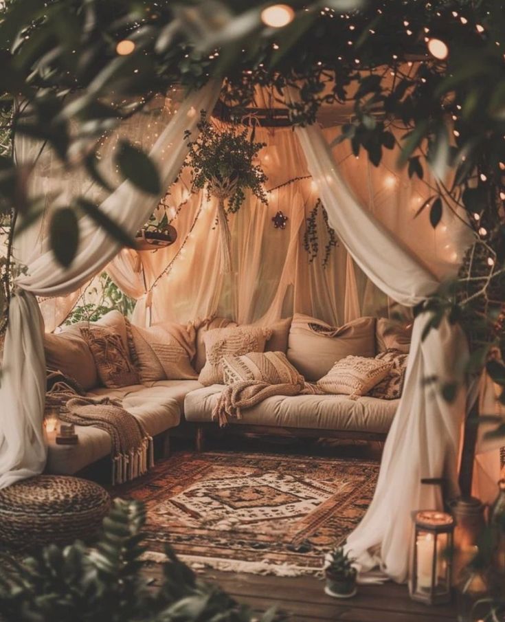 a living room filled with lots of pillows and furniture under a canopy covered in lights