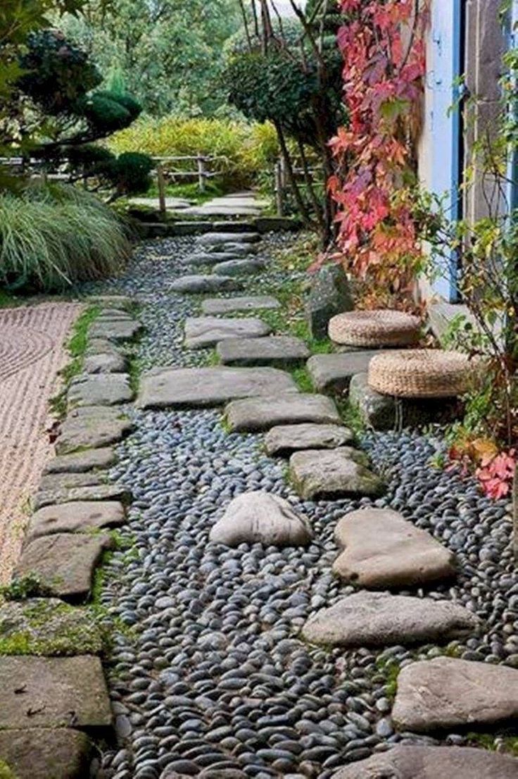 a stone path in the middle of a garden with rocks and plants on either side